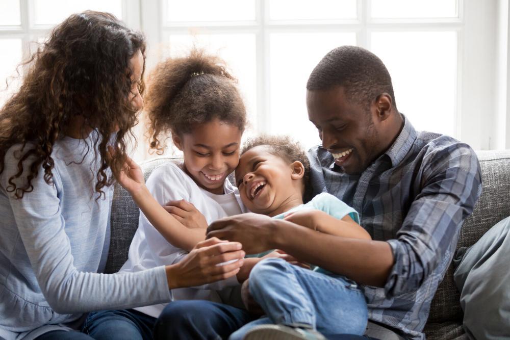 family of four laughing and smiling on the couch