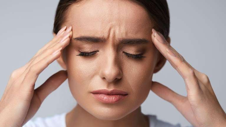 A lady holding her head due to migraines in Kingsway, Burnaby