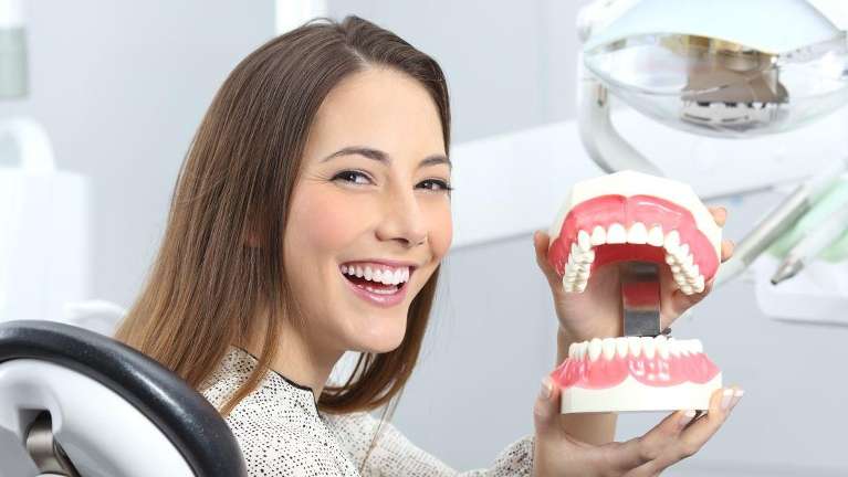 Lady holding an illustration of a dental crown at Central Park Dental Clinic